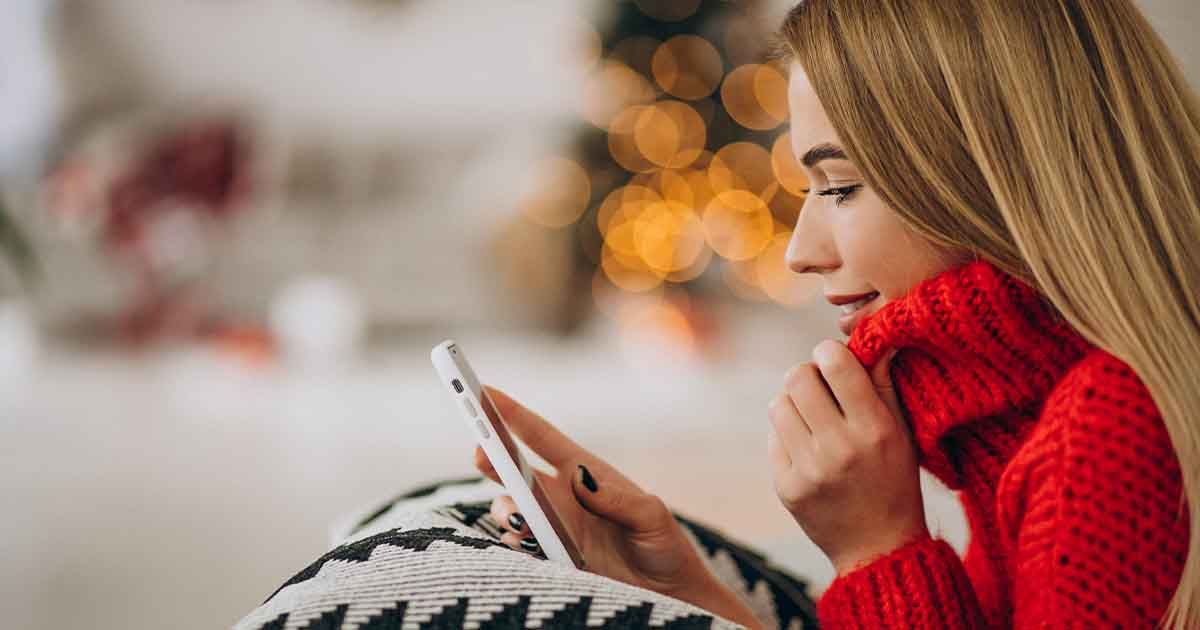 Woman looking at phone, festive background.
