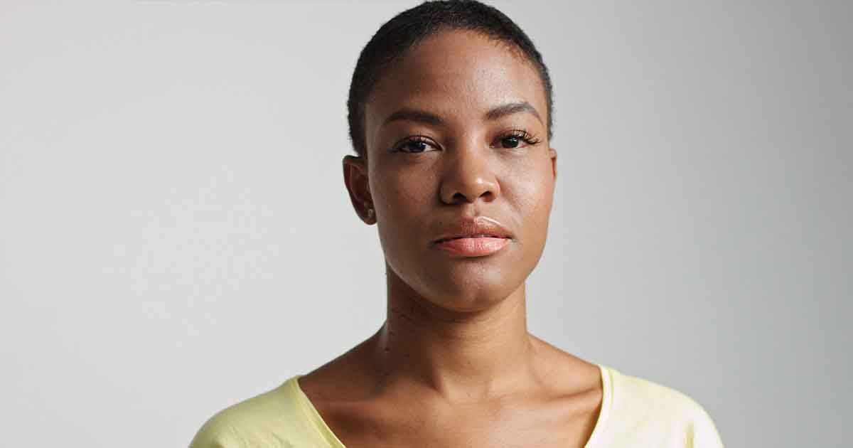 Black woman with short hair, straight face.