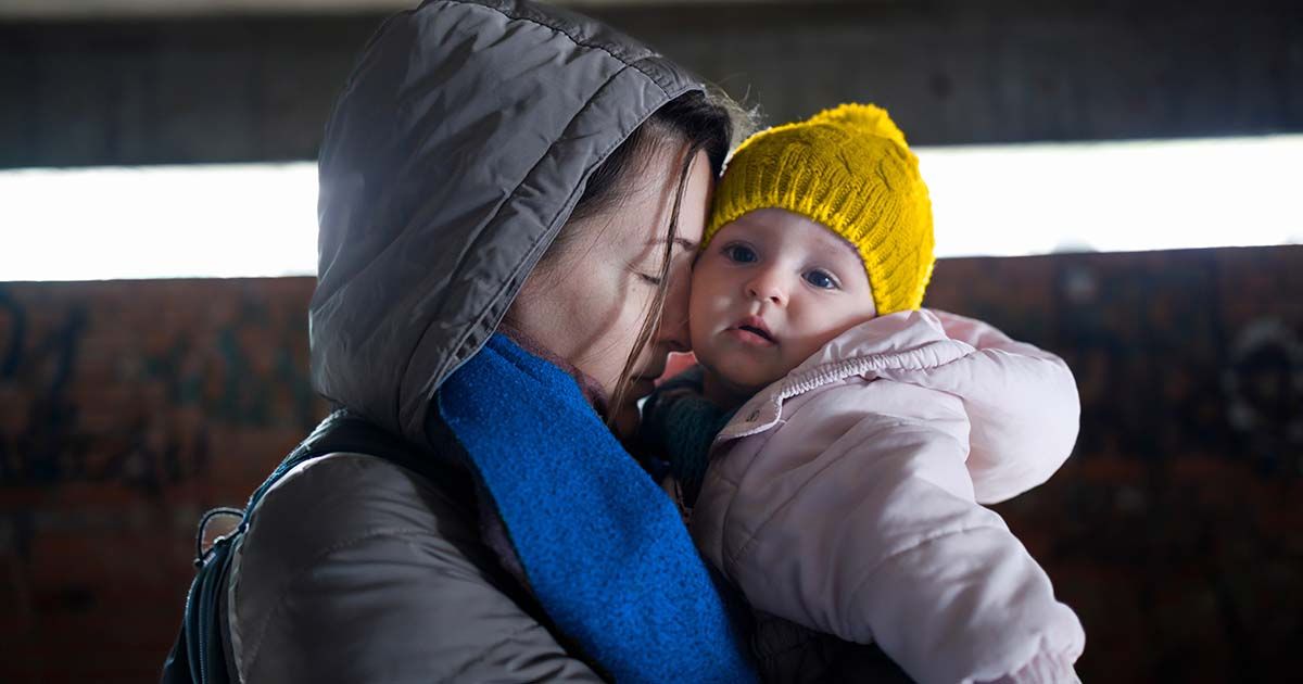 Woman embracing baby while outside in cold weather.