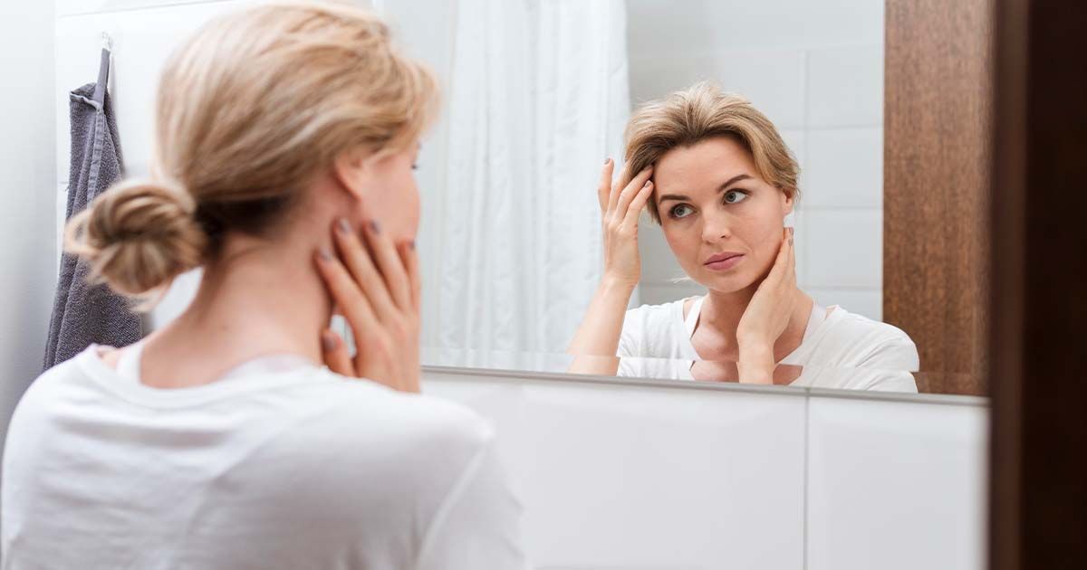 Woman looking in mirror in bathroom.
