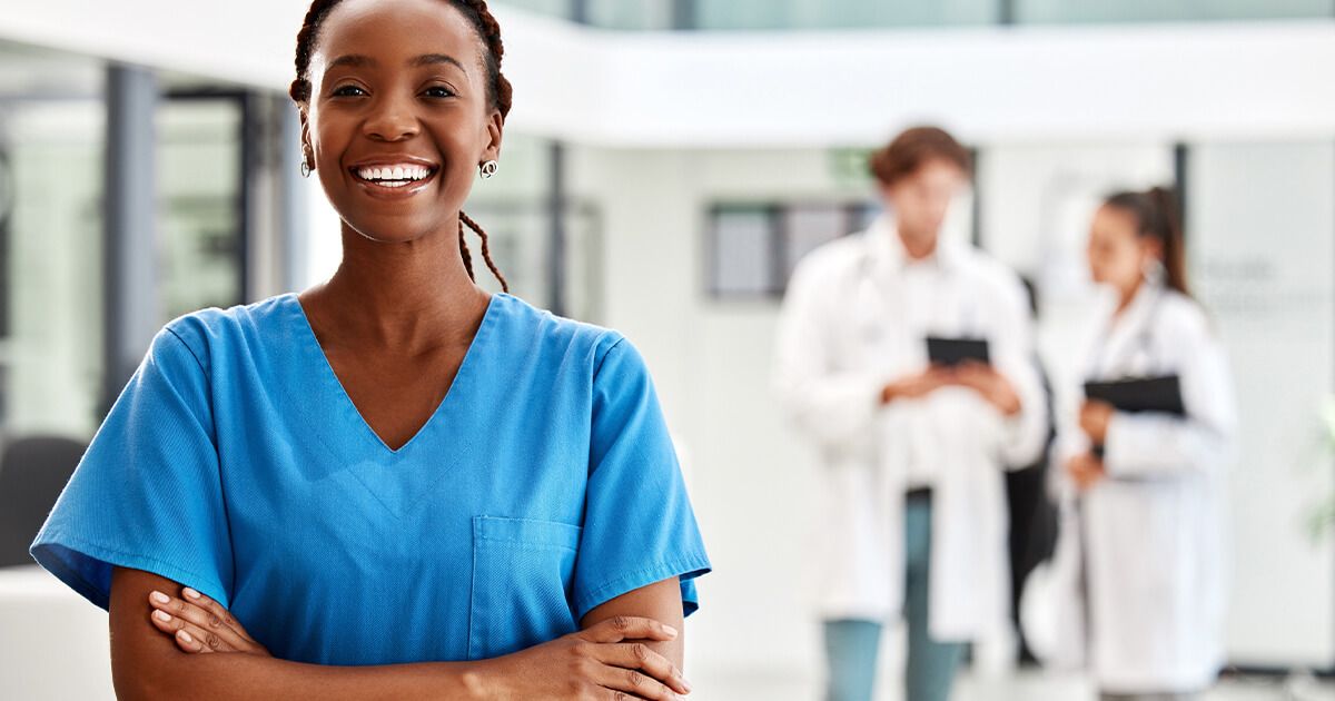 Smiling female nurse with doctor's in background.